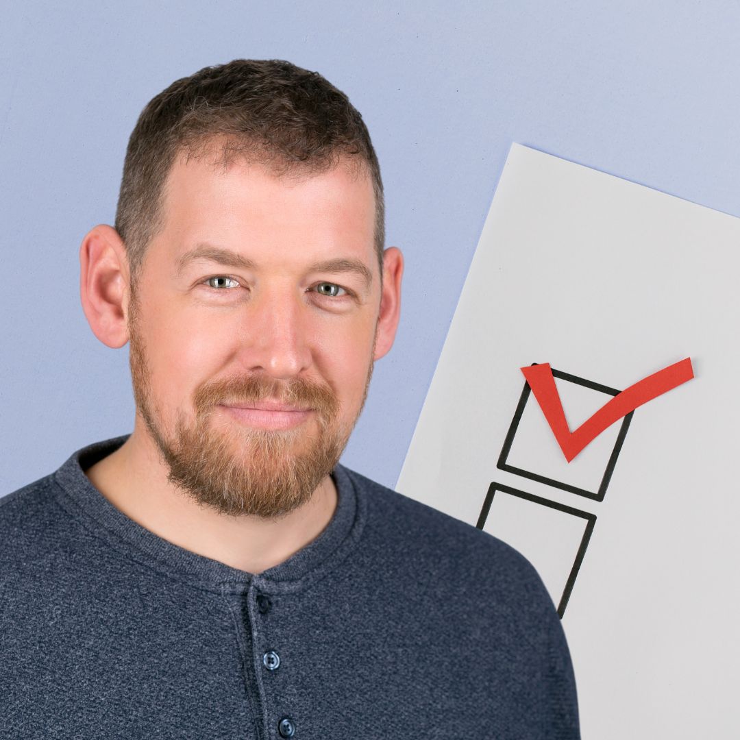 Jamie McAnsh standing in front of a graphic checklist with a red check mark, symbolising moving beyond box-ticking approaches to inclusive workplace culture.
